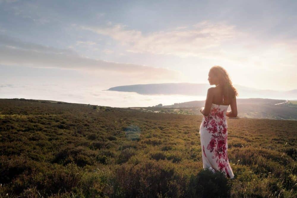 Woman-in-dress-looking-at-sunrise-over-exmoor-devon